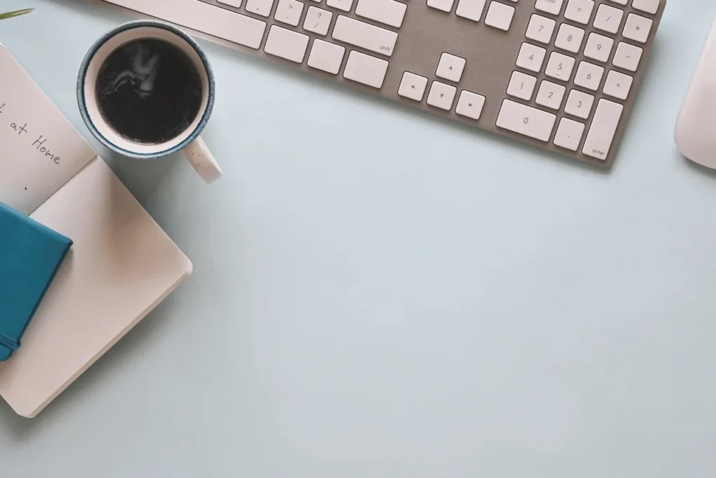 klaveye yanında fincan kahve ve defter